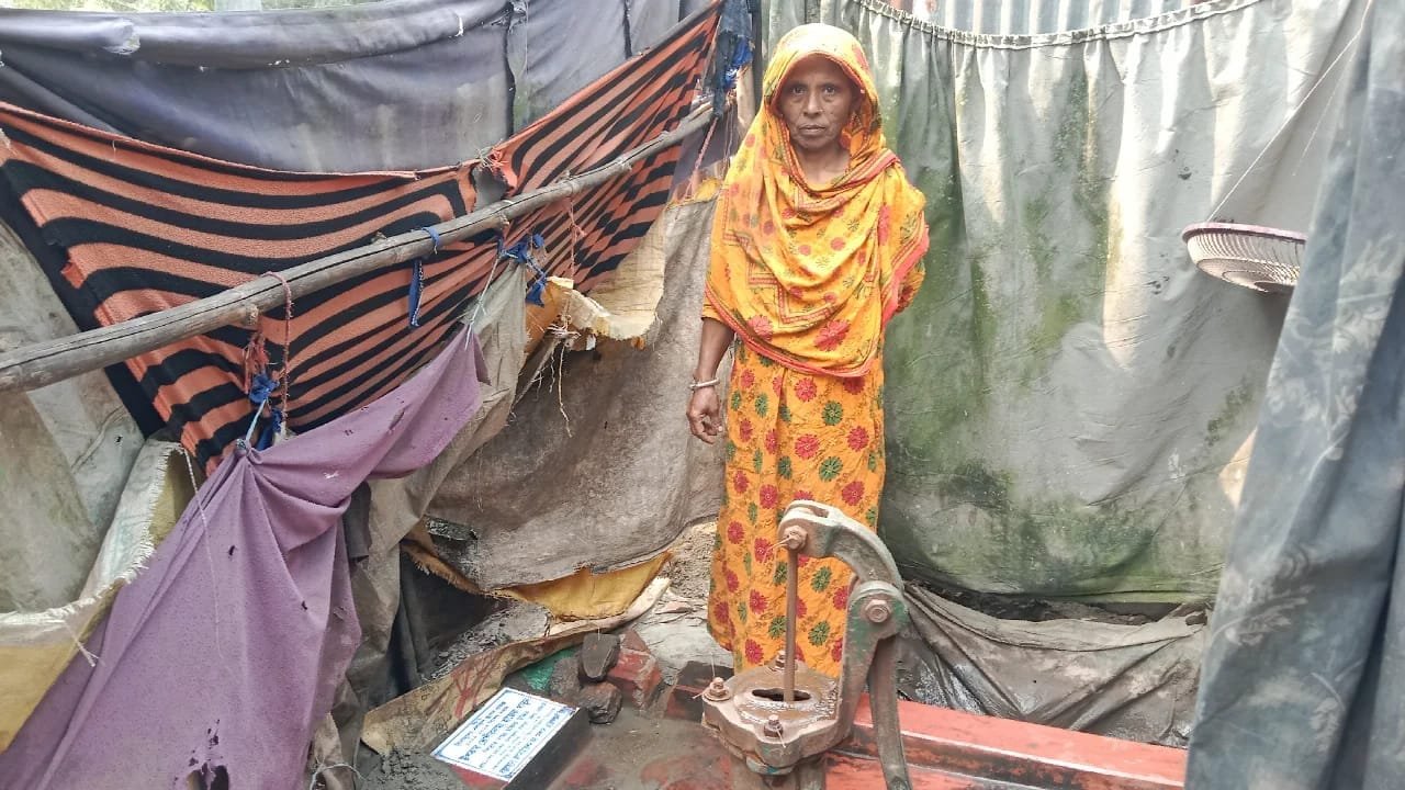 Woman in an orange sari at a hand tube-well